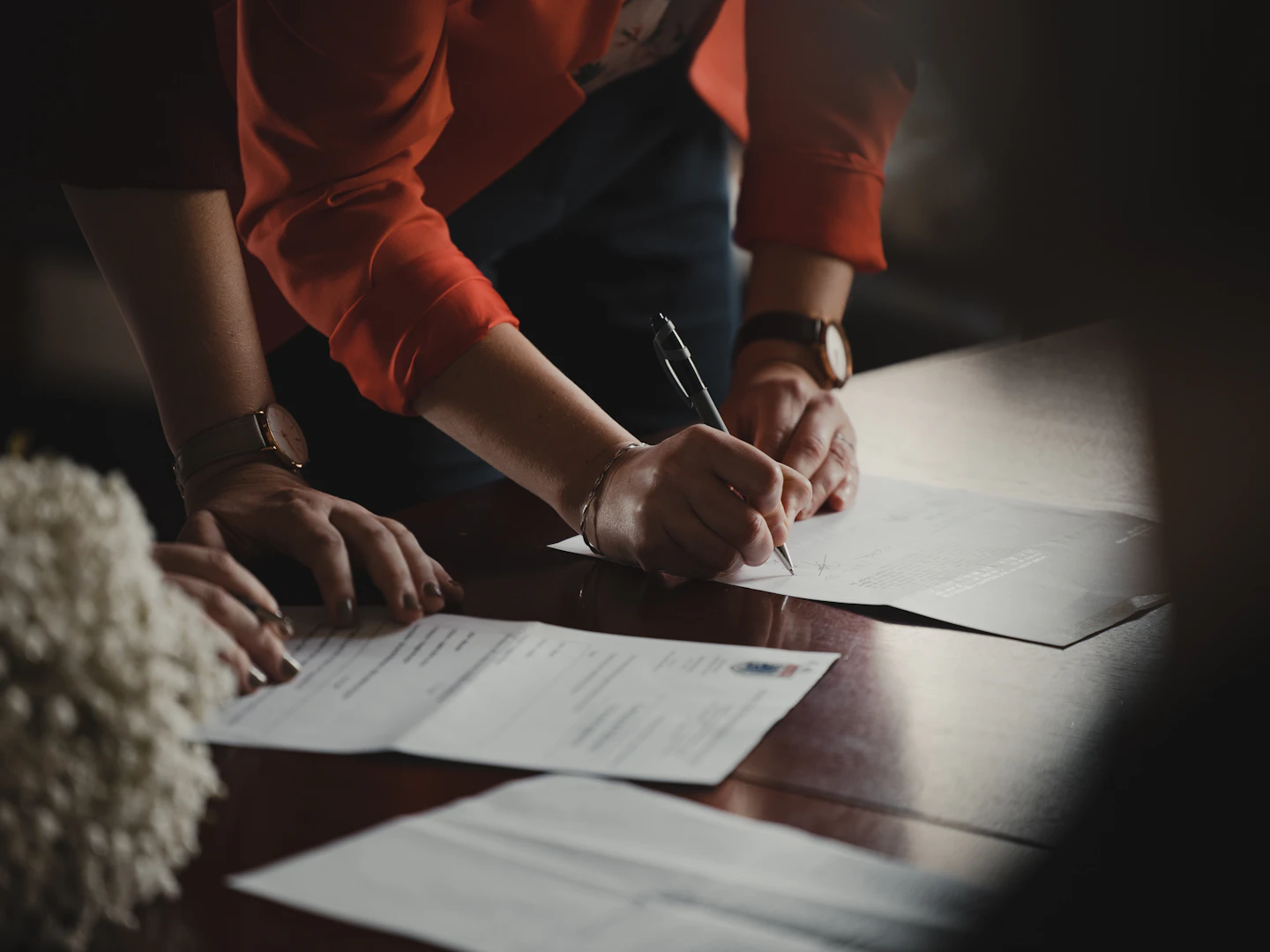 Hands signing and reviewing documents at a table